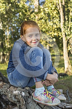 Little girl sitting on the roots of a tree.