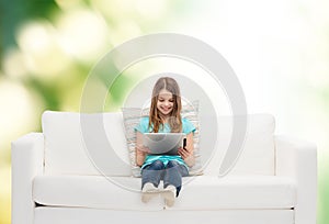 Little girl sitting on sofa with tablet pc