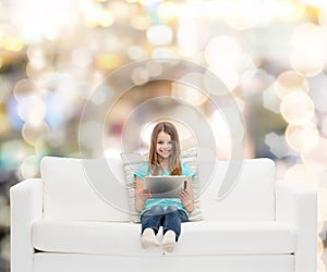 Little girl sitting on sofa with tablet pc