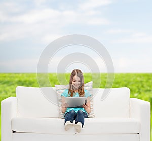 Little girl sitting on sofa with tablet pc