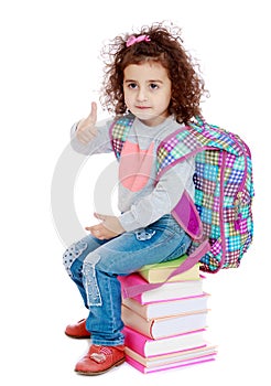 Little girl sitting on stack of books