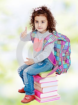 Little girl sitting on stack of books