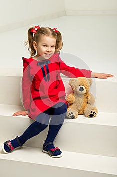 Little girl sitting on stairs with teddy bear