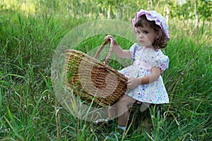Little girl sitting on a stub and holding a basket photo