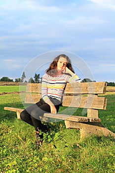 Little girl sitting on sunny bench