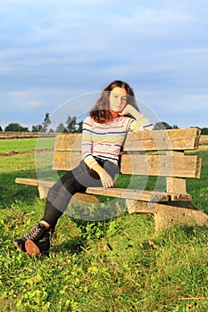 Little girl sitting on sunny bench