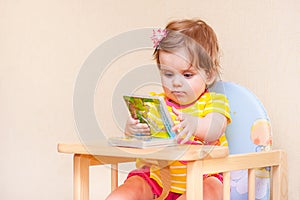Little girl sitting at a table in front of book.