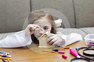 Little girl sitting table putting coin into  Piggy bank house, Money savings concept