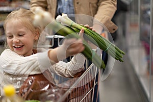 Little girl sitting in the trolley during family shopping in hypermarket