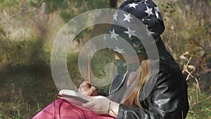 Little girl sitting under the tree and drawing in notebook at park. Beautiful little girl draws outdoors lifestyle