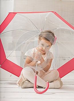 Little girl sitting under an umbrella