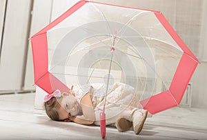 Little girl sitting under an umbrella