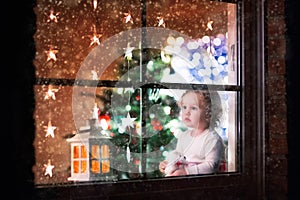 Little girl sitting at a window on Christmas eve