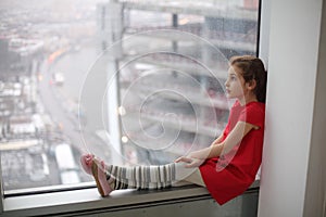 Little girl sitting on the windowsill of a large photo