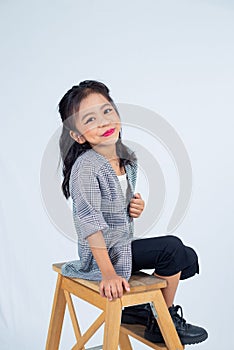 a little girl sitting on a wooden step stool holding a umbrella