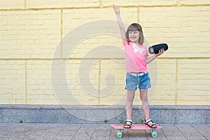 Little girl with a skateboard and listens to music outdoors. Active lifestyle