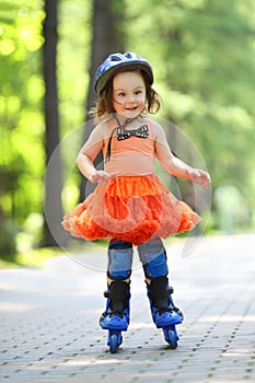 Little girl in skirt and helmet roller-blades and