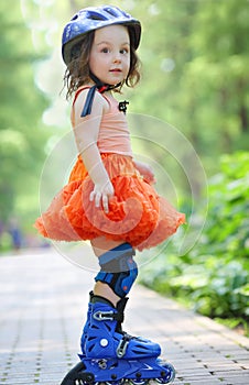 Little girl in skirt and helmet roller skates in