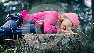 Little girl sleaping on a cut tree trunk