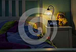 Little girl sleeping in bed - Alarm clock at 6 am in the morning.
