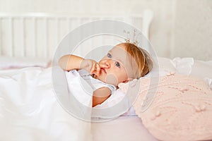 Little girl sleeping in bed in bedroom with crown. Princess birthday party.