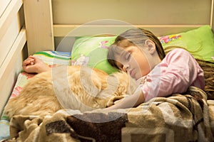 Little girl sleeping in bed with cat