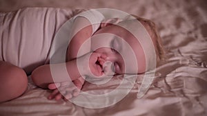 Little girl sleeping on bed with a finger in her mouth