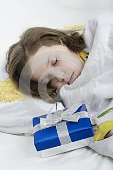 Little girl sleeping in bed with gift