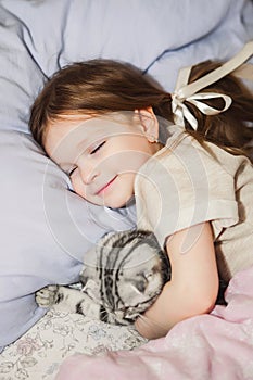 Little girl sleeping in bed with her cat