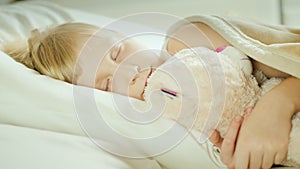 Little girl sleeping in bed with her pet toy