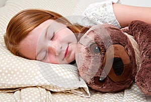 Little girl sleeping in bed hugging the teddy bear