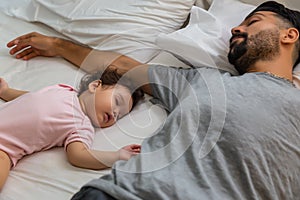 Little girl sleeping on bed near her father in bedtime. Single father get tired and sleeping together with his beloved infant