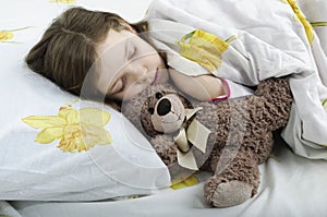 Little girl sleeping in bed with teddy bear