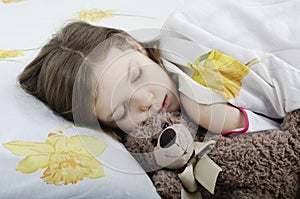 Little girl sleeping in bed with teddy bear