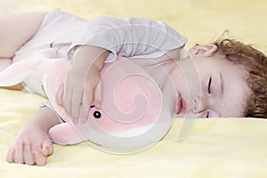 Little girl sleeping boy hugging a toy pink whale. Little Caucasian child sleeps with a soft toy