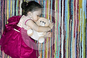 Little girl sleeping on a colorful rug.