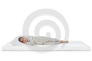 Little girl sleeping on comfortable mattress against white background