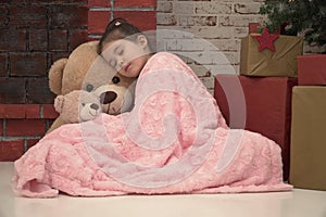 Little girl sleeping with huge plush bear on the floor waiting for Santa
