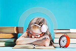 Little girl sleeping on an open book in funny red glasses