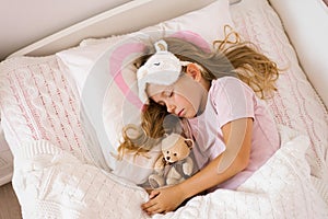 Little girl sleeping with a soft toy in her bed on a pillow is a sweet calm sleep of a child