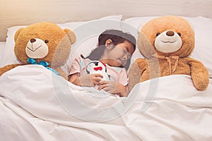 Little girl sleeping with teddy bear in bed