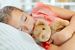 Little girl sleeping with teddy bear toy at home