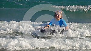 Little girl slides on a wave on a little surfboard