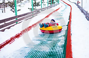 Little girl sliding down the hill by tubing