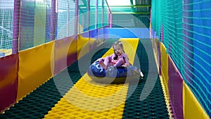 Little girl sliding down on the tubing in the game center