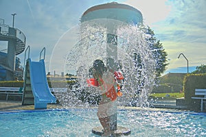 Little girl in the small swimming pool. Cute girl take shower in water park. Summer and happy chilhood concept