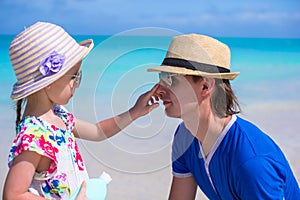 Little girl smearing her dad's nose Sun Protection Cream