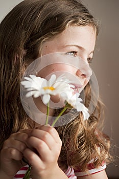 Little girl smelling daisies