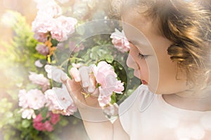 Little girl smelling flower on blurred hazy background photo