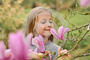 A little girl smelling a pink magnolia